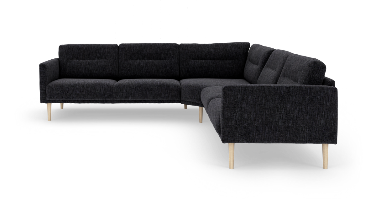 Mørkegrå L‑formet modul-/hjørnesofa med lyse træben og polstrede rygpuder, frilagt på hvid baggrund.