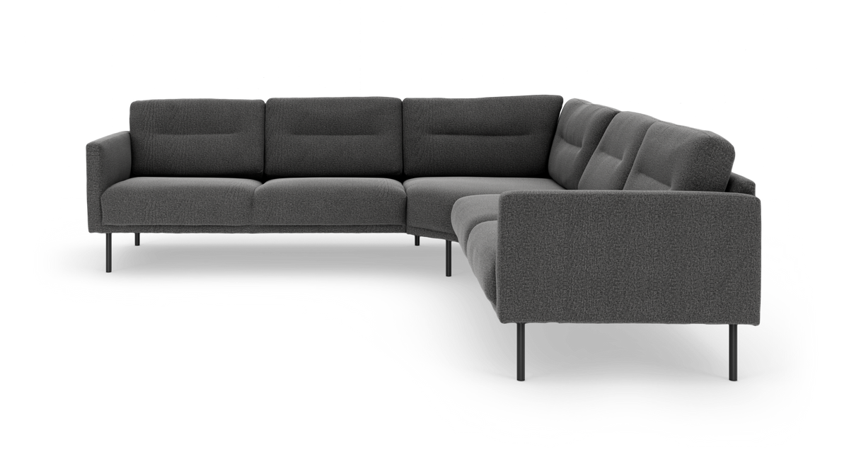 Mørkegrå L‑formet hjørnesofa i stof med slanke sorte metalben, fotograferet i studie.