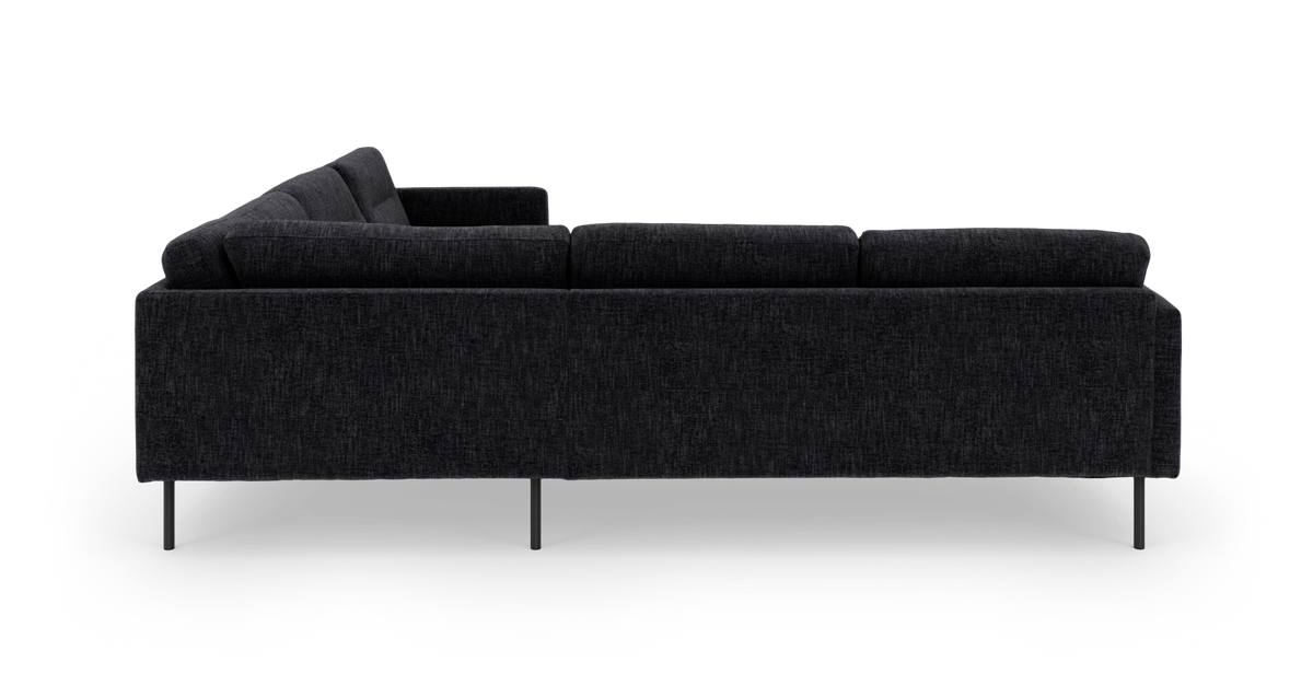 Mørkegrå stofsofa set fra siden på hvid baggrund.