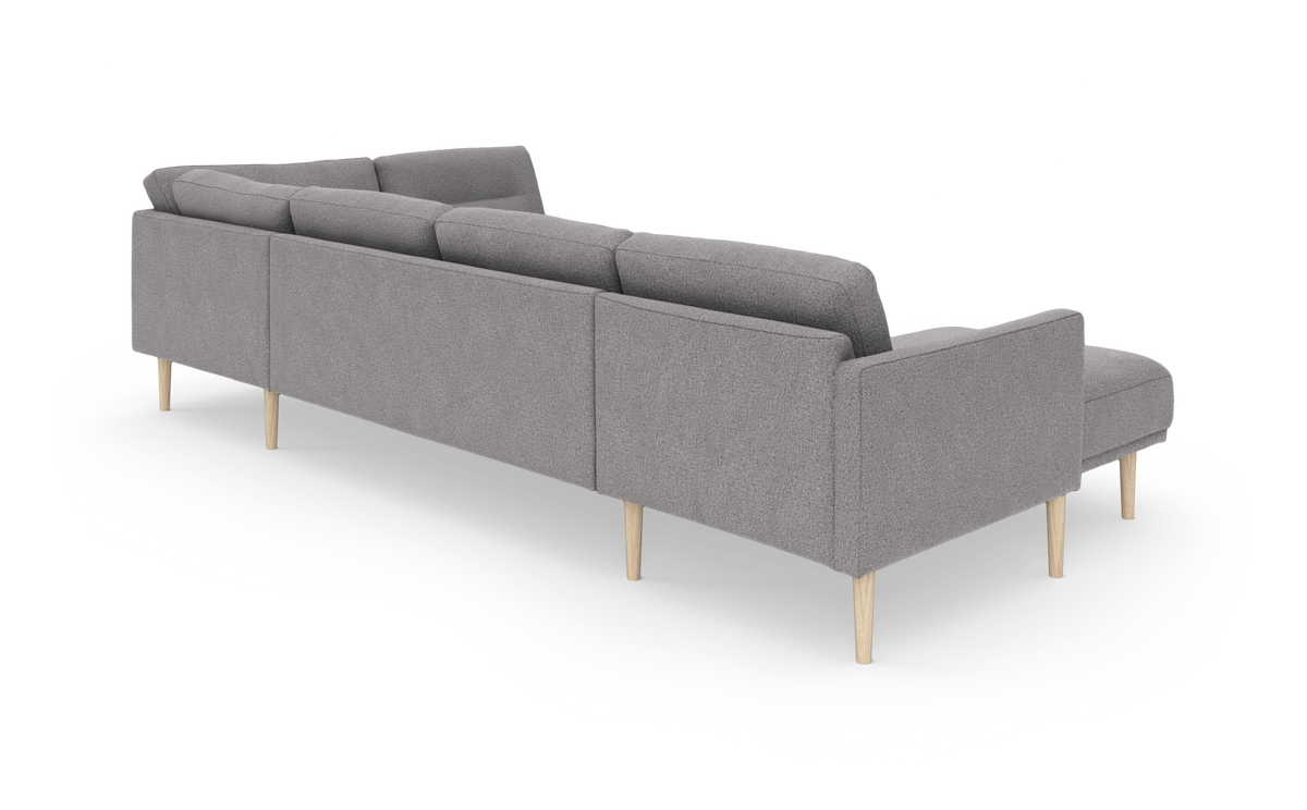Grå modulsofa med chaiselong, set bagfra i skrå vinkel på hvid baggrund.