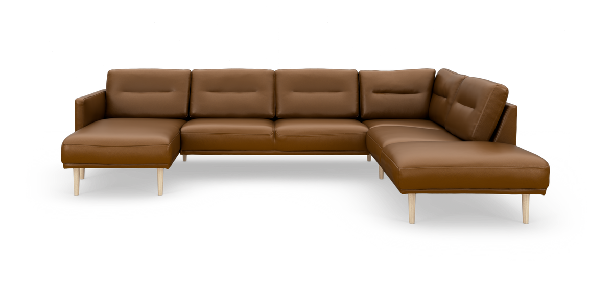 Brun læderhjørnesofa med chaiselong og lyse træben, fotograferet skråt forfra i studie på hvid baggrund.