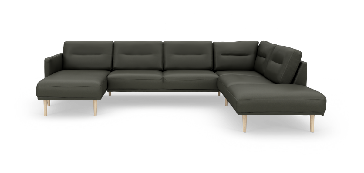 Mørkegrøn U‑formet modulsofa med chaiselong til venstre og lyse træben, frilagt mod hvid baggrund.