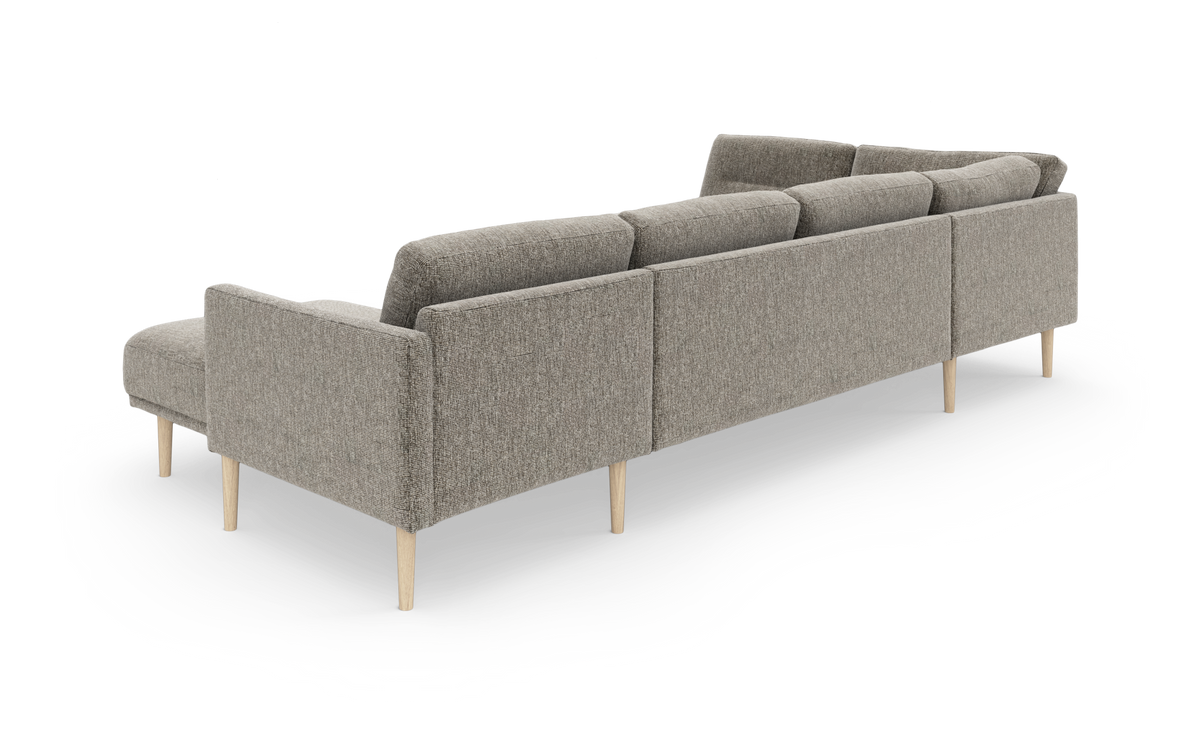 Grå modulsofa med chaiselong og slanke træben, set bagfra i skrå vinkel, frilagt på hvid baggrund.