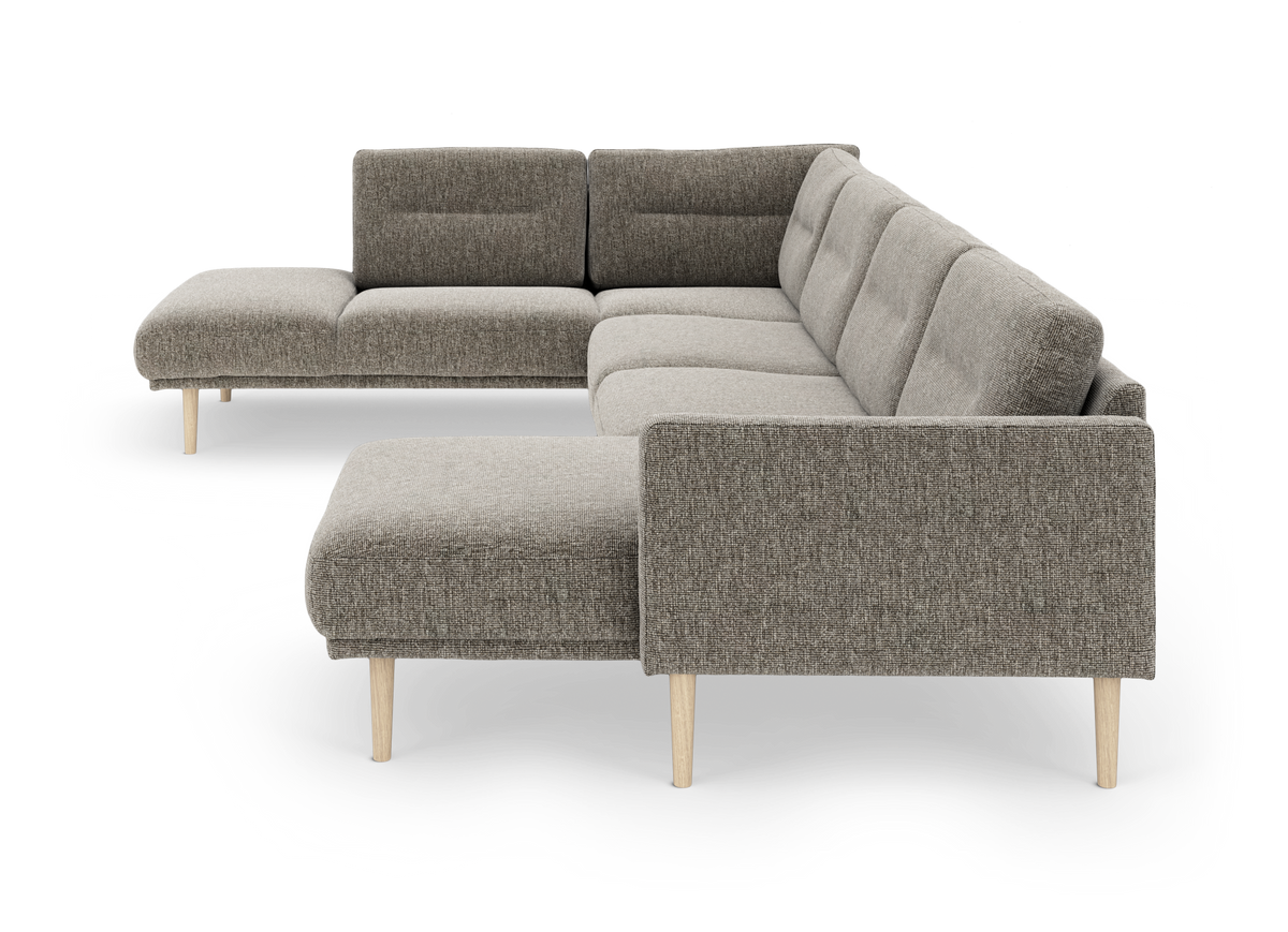 Modulær L‑sofa i gråt stof med chaiselong og lyse træben, frilagt på hvid baggrund.