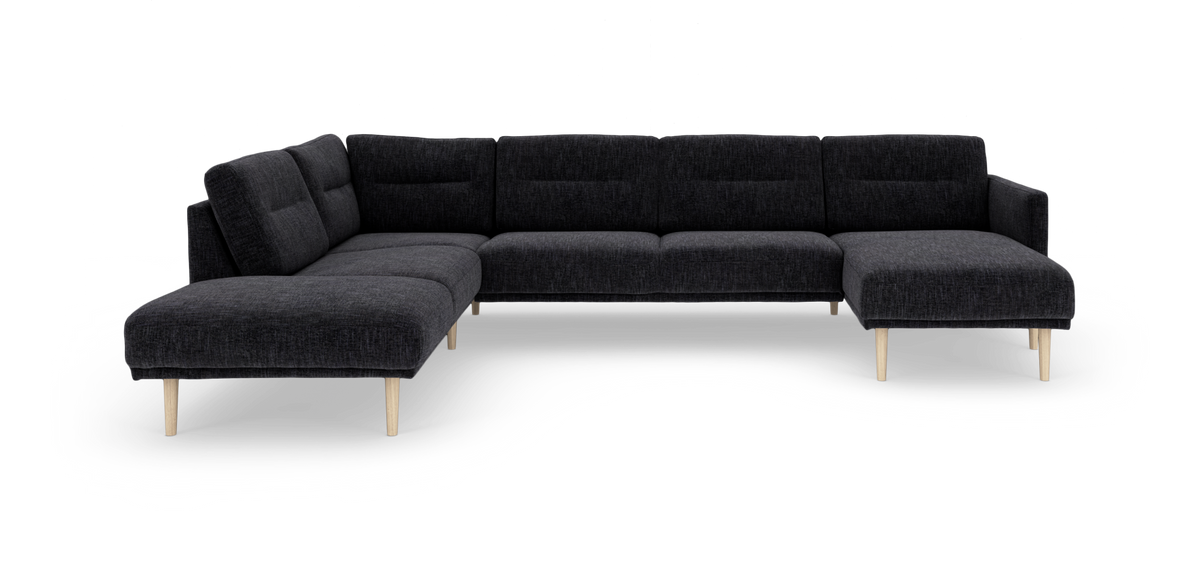 Mørkegrå modulsofa i hjørne/U‑form med chaiselong til højre og lyse træben, frilagt.