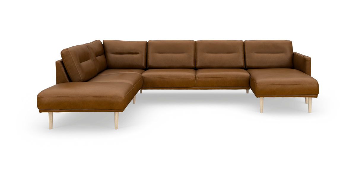 Brun hjørnesofa i læder med chaiselong til højre og slanke lyse træben, frilagt produktbillede.