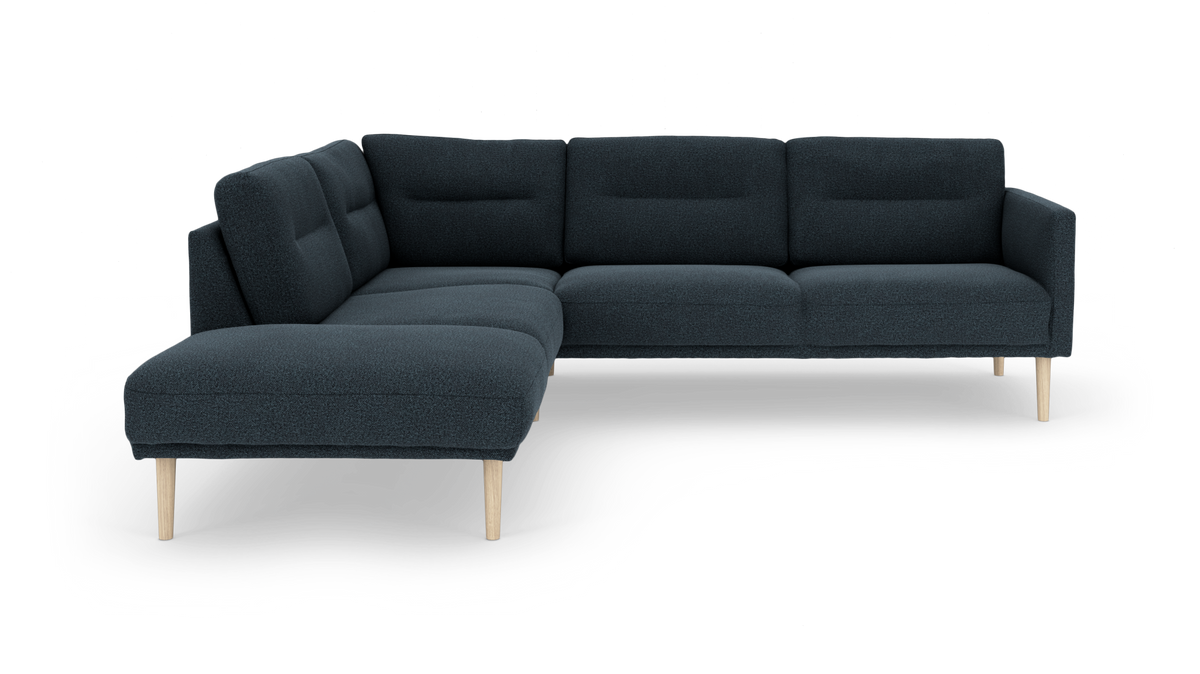 Mørkeblå hjørnesofa med chaiselong til venstre og lyse træben på hvid studiebaggrund.
