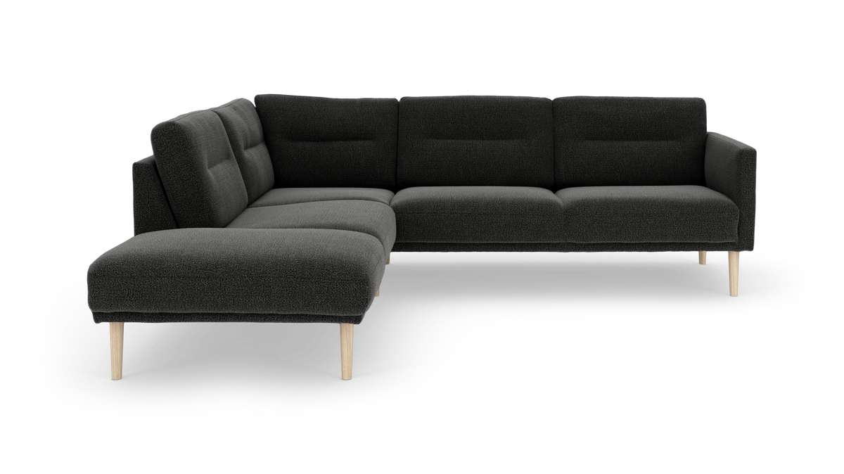 Mørkegrå L‑sofa med venstrevendt chaiselong og lyse træben, moderne og polstret, frilagt på hvid baggrund.