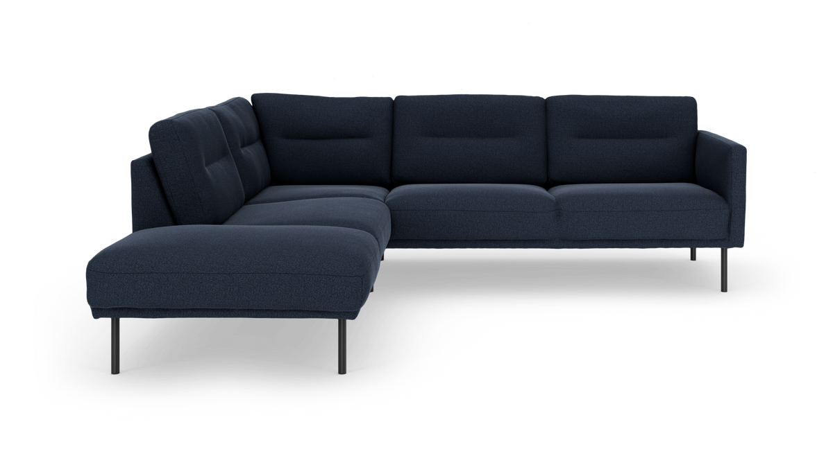 Mørkeblå L‑formet modulsofa med chaiselong til venstre på slanke metalben, frilagt på hvid baggrund.