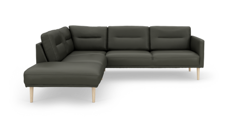 Mørkegrøn L-sofa med chaiselong til venstre og lyse træben, frilagt på hvid baggrund.