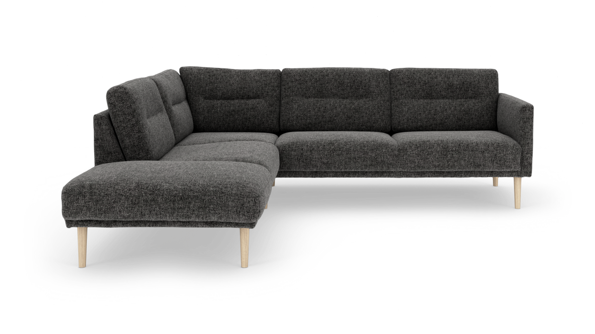 Mørkegrå hjørnesofa med chaiselong til venstre og lyse træben, frilagt produktfoto på hvid baggrund.