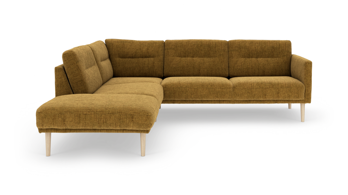 Sennepsgul L-sofa med venstrevendt chaiselong og lyse træben, frilagt i studie.