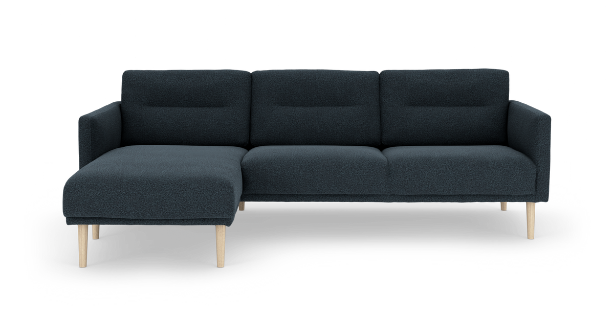 Mørkeblå hjørnesofa med venstre chaiselong og lyse træben, frilagt på hvid baggrund.