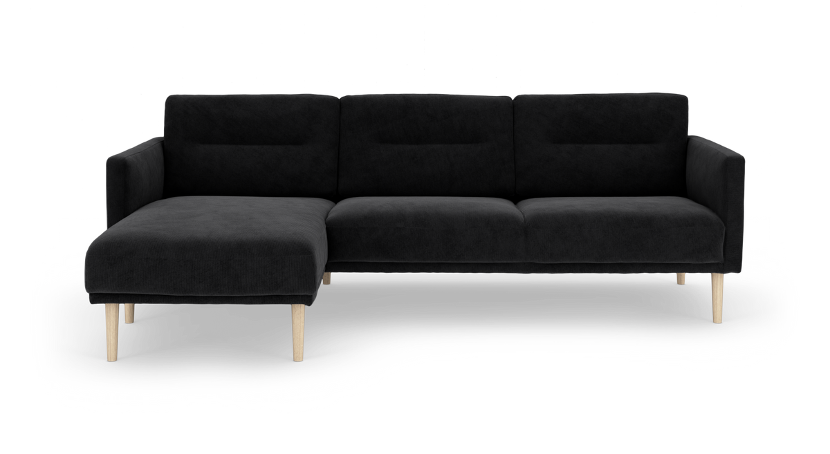 Sort hjørnesofa med chaiselong til venstre og lyse træben, frilagt på hvid baggrund.