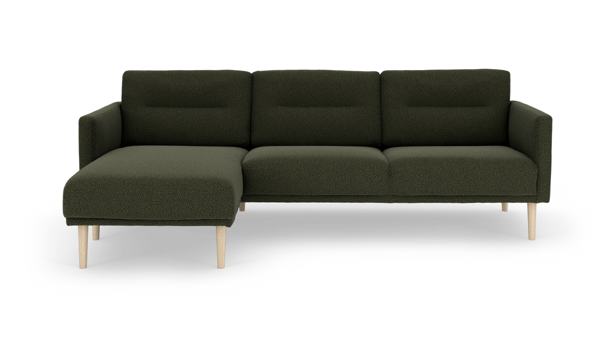 Mørkegrøn modulsofa med venstrevendt chaiselong og lyse træben, frilagt på hvid baggrund.