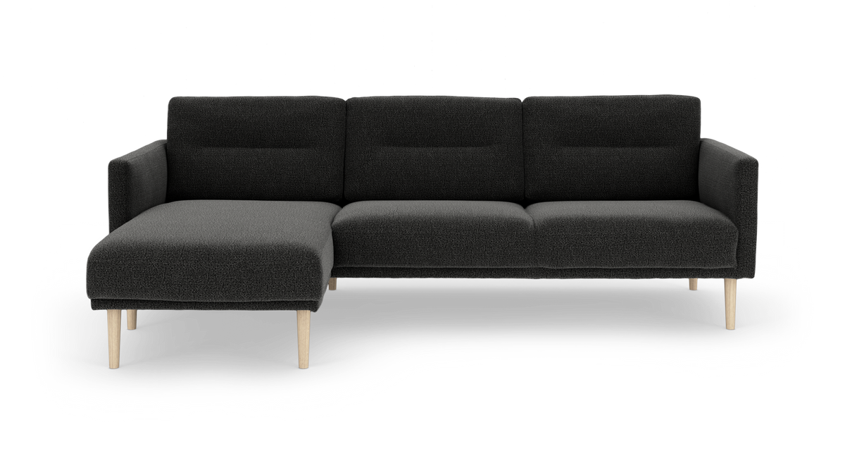 Mørkegrå hjørnesofa med venstrevendt chaiselong og lyse træben, fritlagt på hvid baggrund.