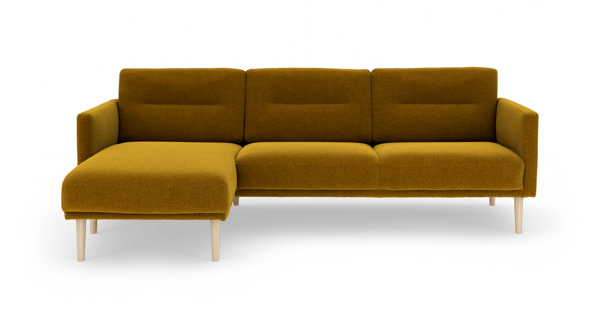 Sennepsgul hjørnesofa med venstrevendt chaiselong og lyse træben, isoleret på hvid baggrund.