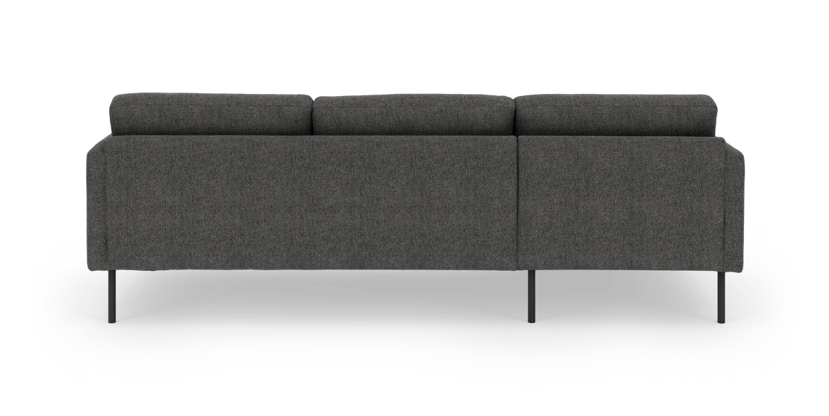 Mørkegrå stofsofa set bagfra med slanke sorte ben, frilagt på hvid baggrund.