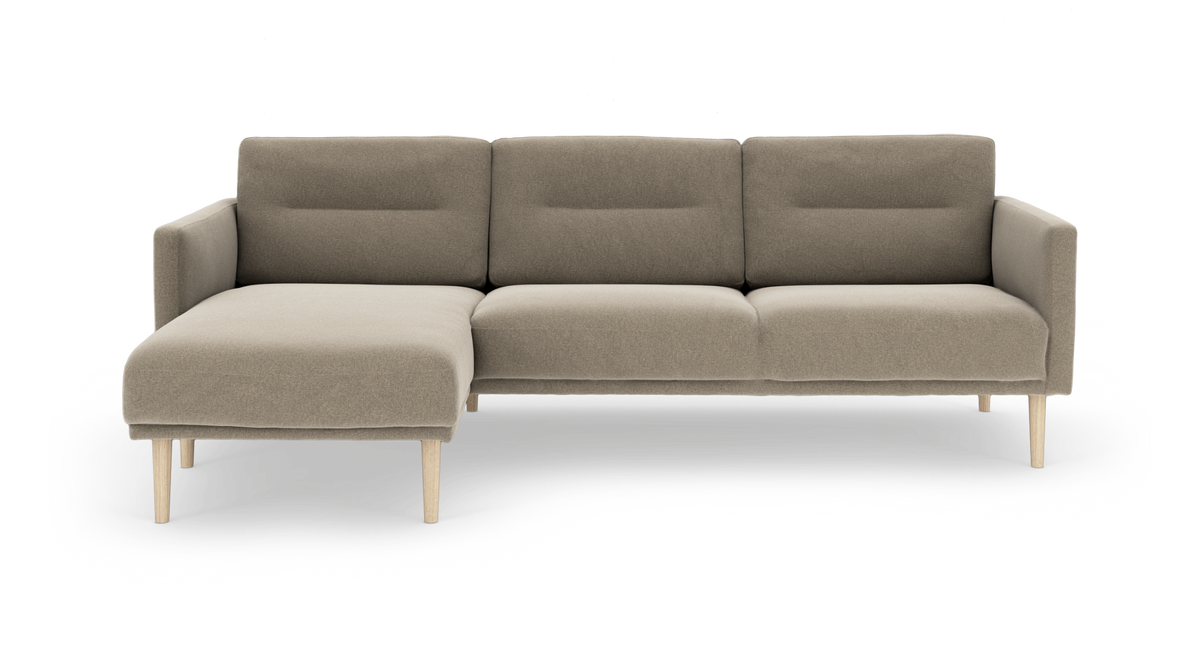 Beige modulsofa med venstrevendt chaiselong, stofbetrukket med lyse træben, frontvisning mod hvid baggrund.