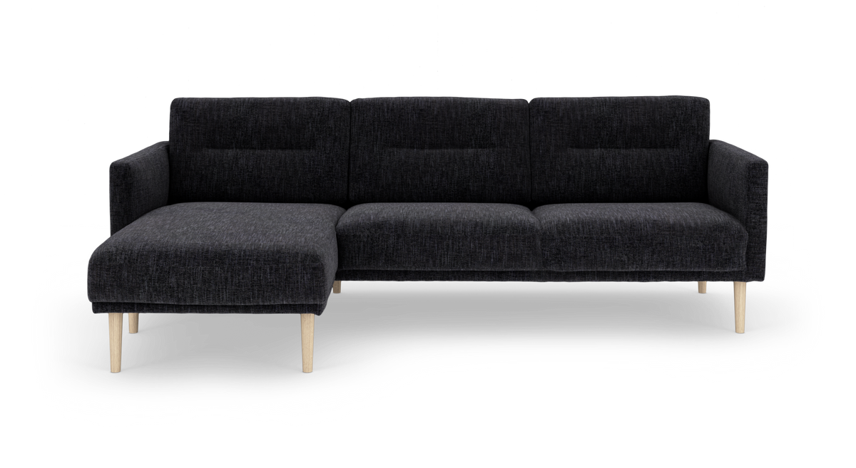 Mørkegrå modulsofa med venstrevendt chaiselong og lyse træben, frilagt på hvid baggrund.