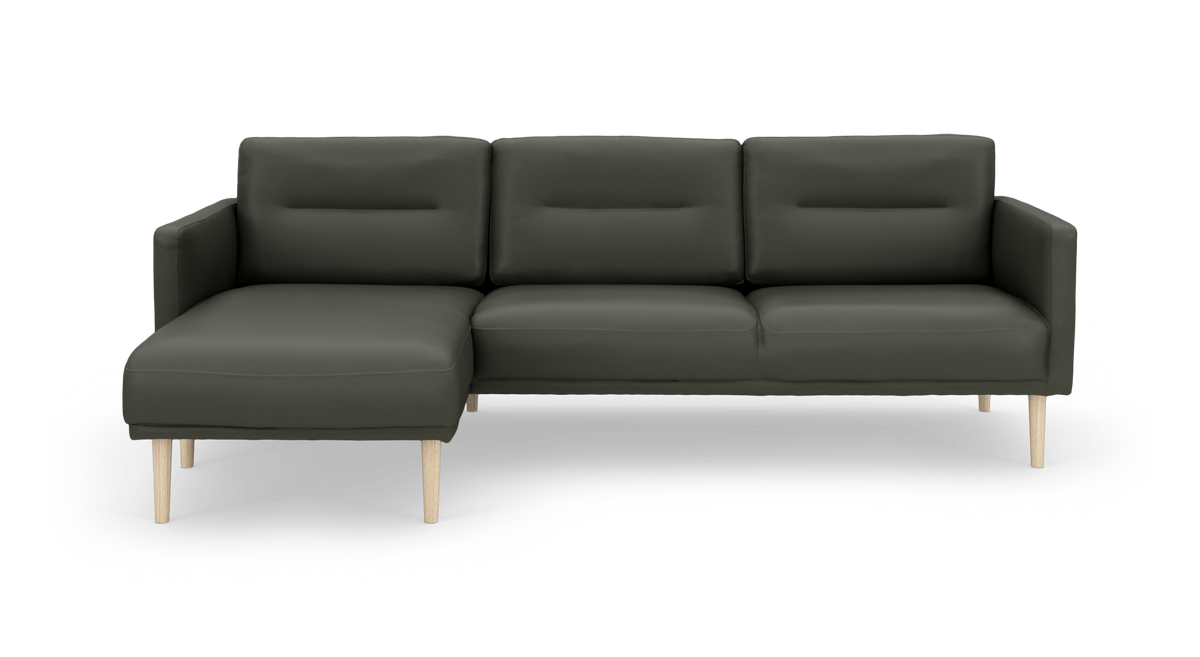 Mørkegrøn 3-personers sofa med venstrevendt chaiselong og lyse træben, frilagt på hvid baggrund.