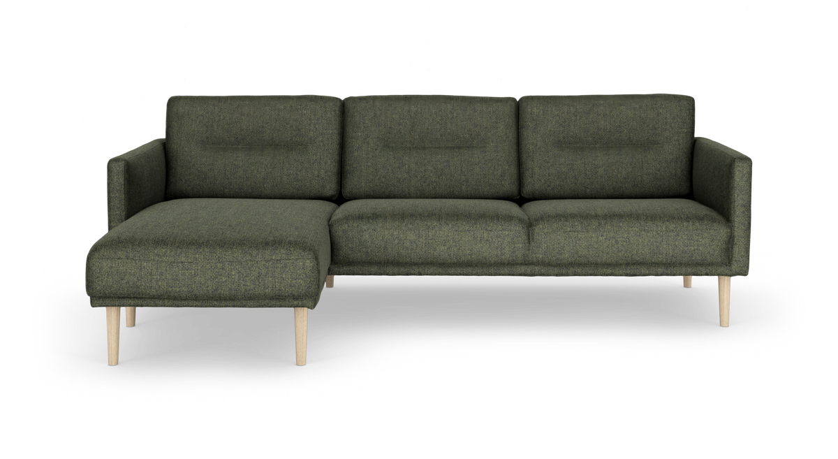 Grøn modulsofa med venstrevendt chaiselong og lyse træben, frilagt.