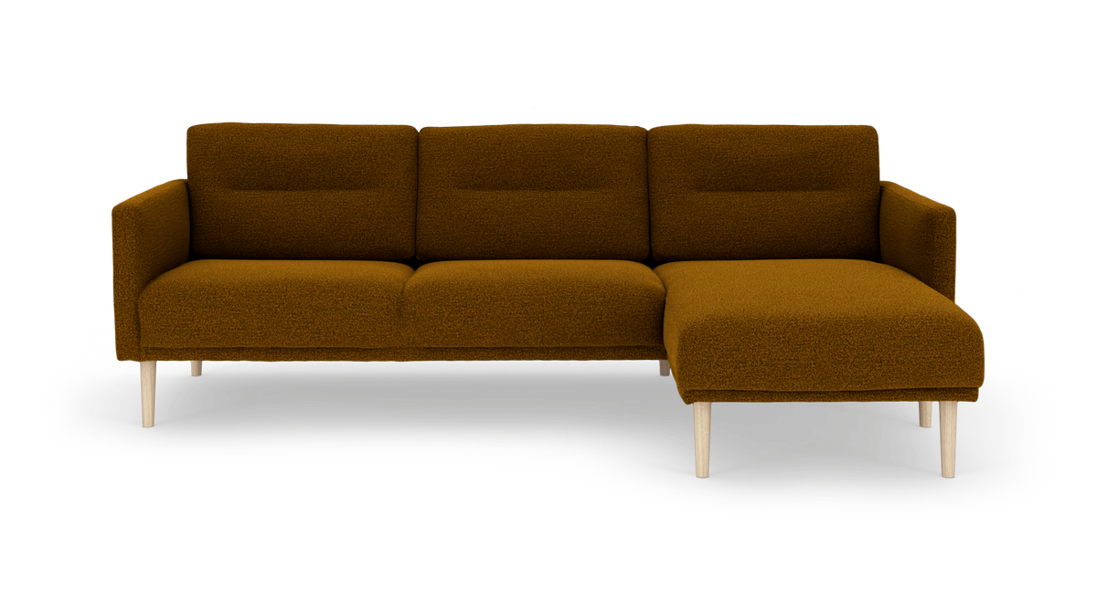 Varmt rustbrun hjørnesofa i bouclé med højrevendt chaiselong og lyse træben, frilagt på hvid baggrund.