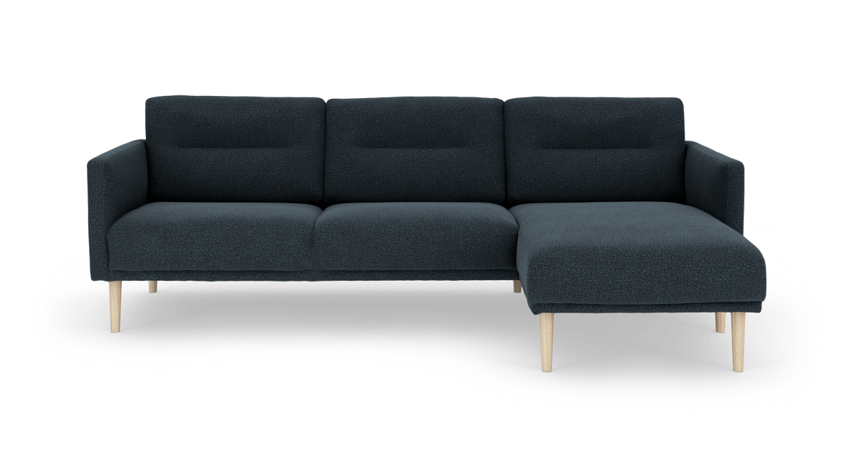 Mørkeblå modulsofa med chaiselong til højre og lyse træben, frilagt på hvid baggrund.