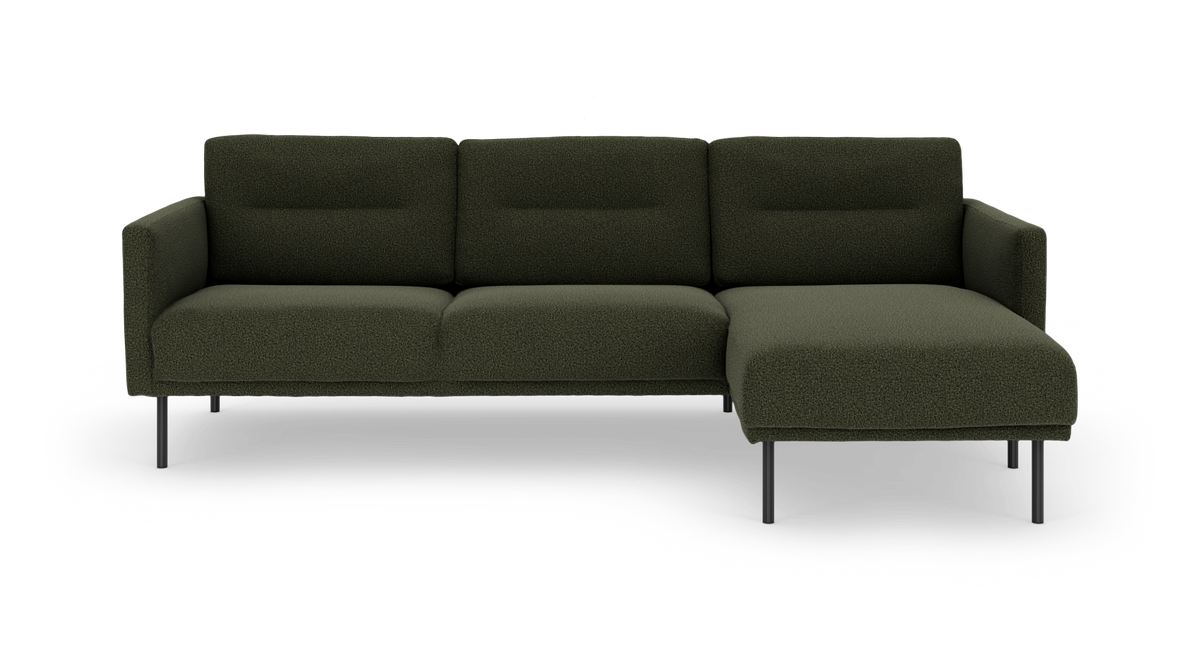 Mørkegrøn modulsofa i stof med chaiselong til højre og slanke metalben, fotograferet forfra.