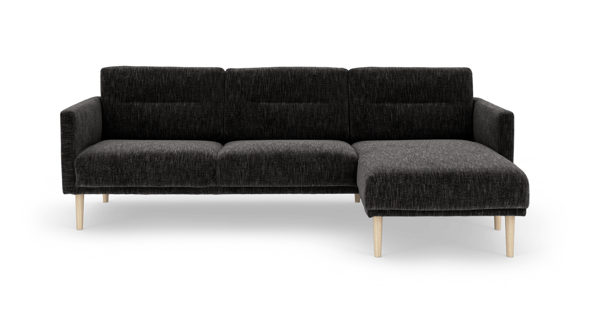 Mørkegrå hjørnesofa med chaiselong til højre og lyse træben.