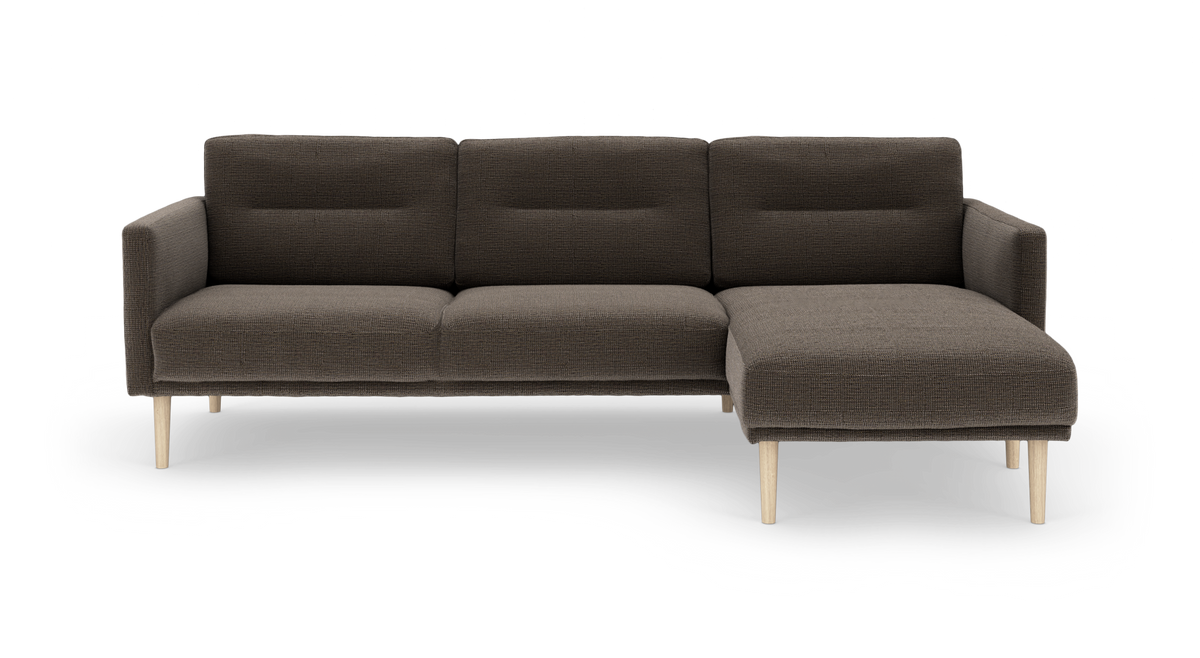 Mørkebrun hjørnesofa med chaiselong til højre og lyse træben, frilagt på hvid baggrund.