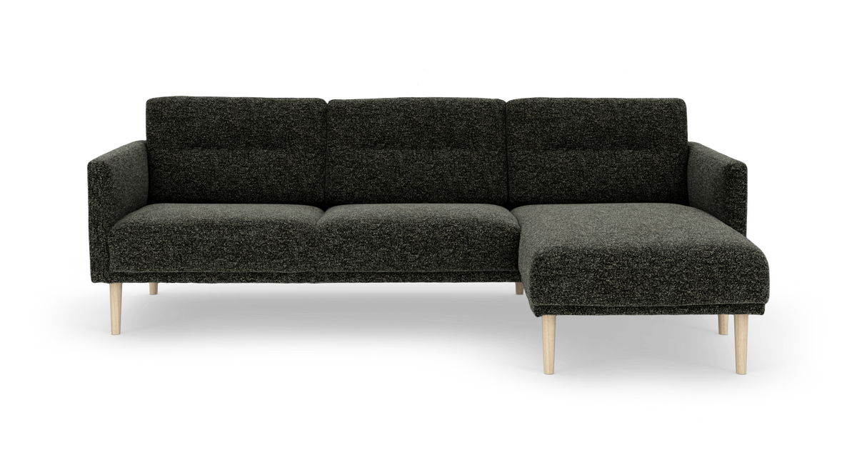 Mørkegrå hjørnesofa med chaiselong til højre på lyse træben, fritlagt på hvid baggrund.