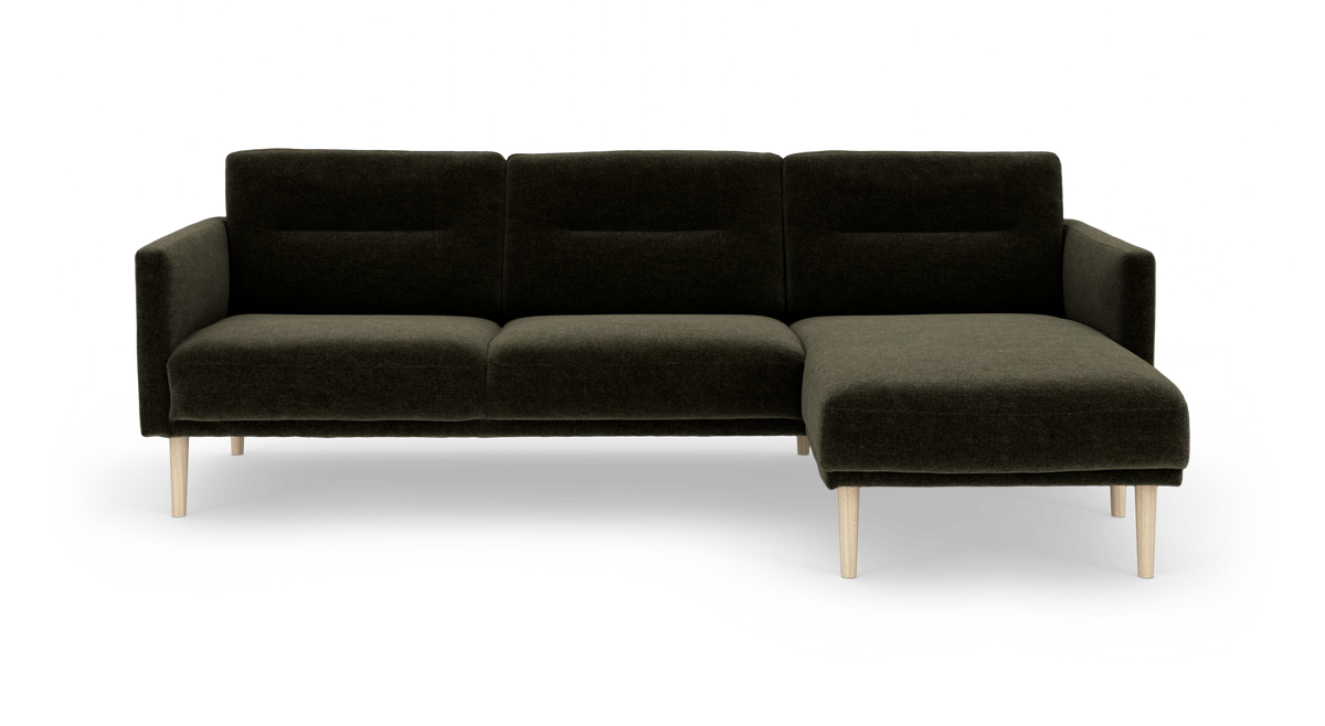 Mørkegrøn hjørnesofa med chaiselong til højre og lyse træben, set forfra.