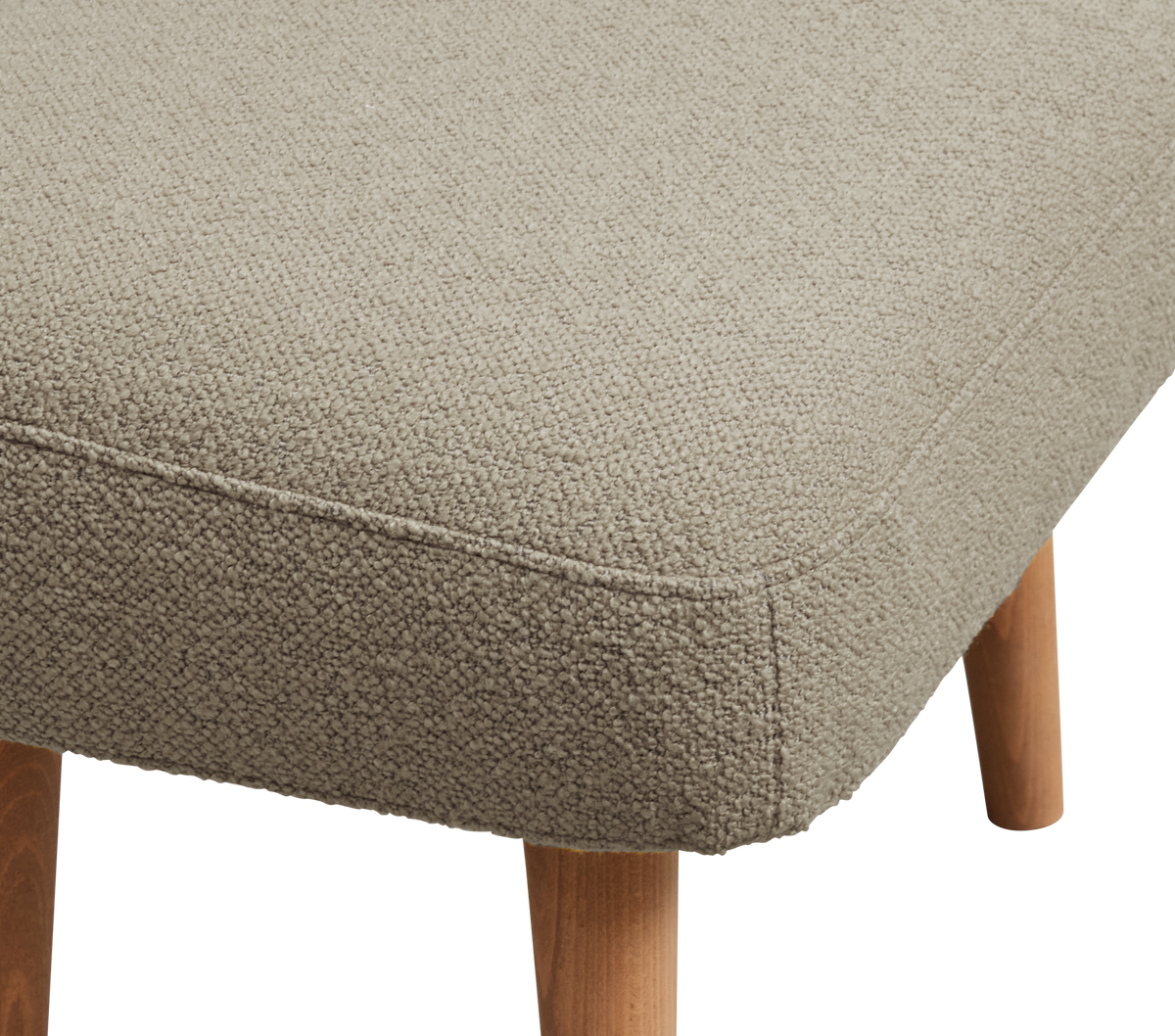 Nærbillede af beige bouclé-betrukket skammel/puf med afrundet syning og lyse træben.