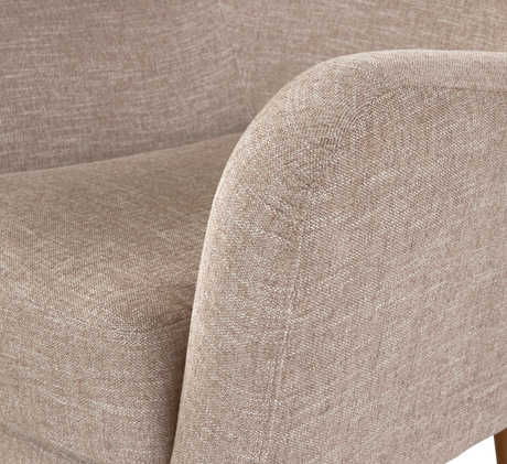 Nærbillede af beige stofbetrukket lænestol/sofa med afrundet armlæn og sæde i moderne stil.