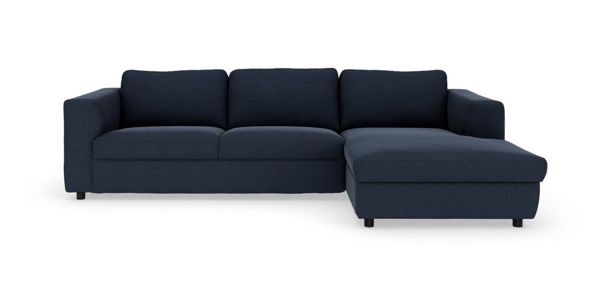 Mørkeblå hjørnesofa med chaiselong til højre, set forfra på hvid studiebaggrund.
