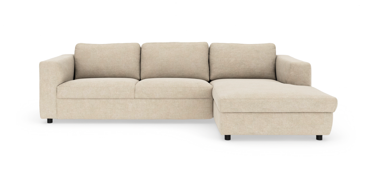 Beige hjørnesofa med chaiselong på højre side, tre sæder, stofbetræk og lave sorte ben, frilagt på hvid baggrund.