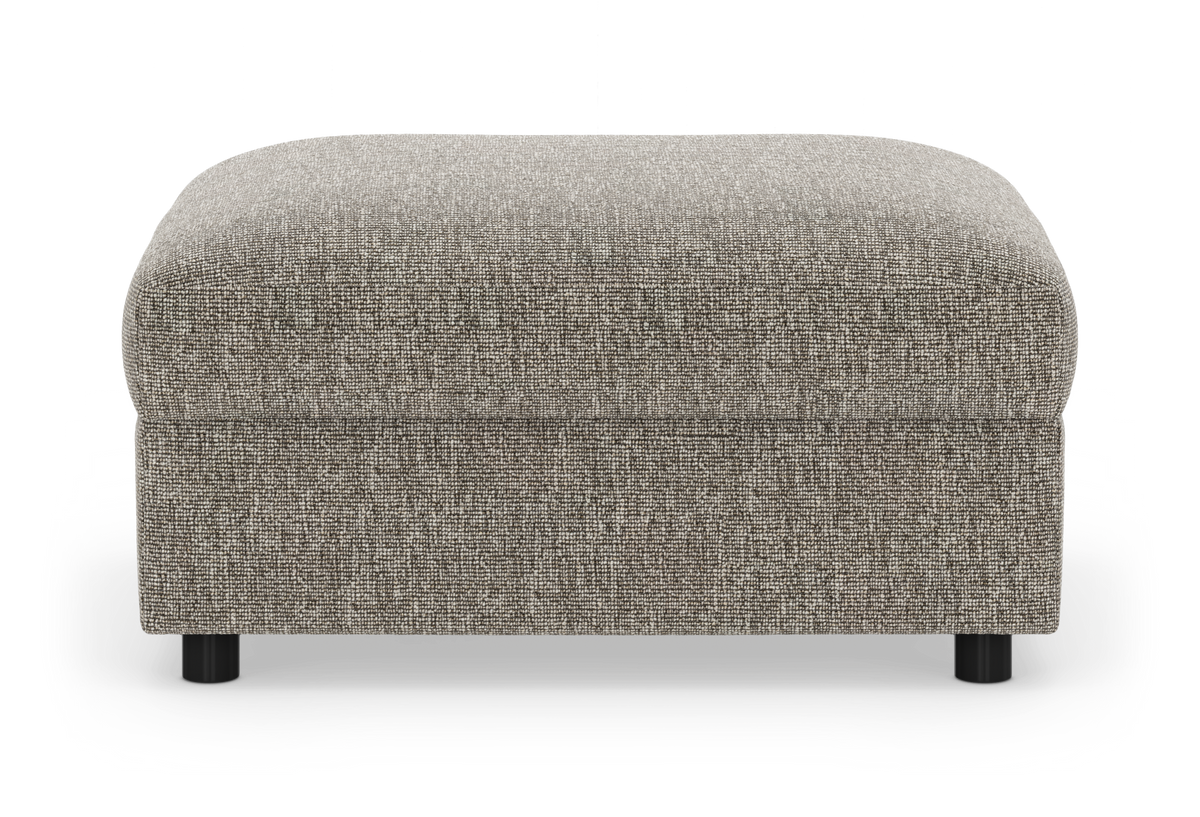 Rektangulær grå‑beige puf/ottoman i tekstil med runde sorte ben, fritlagt på hvid baggrund.
