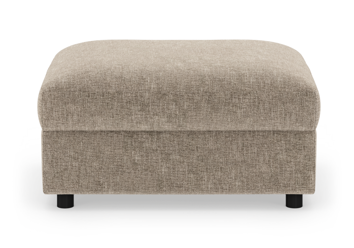 Beige stofbetrukket ottoman/fodskammel med afrundede hjørner og sorte runde ben, frilagt mod hvid baggrund.