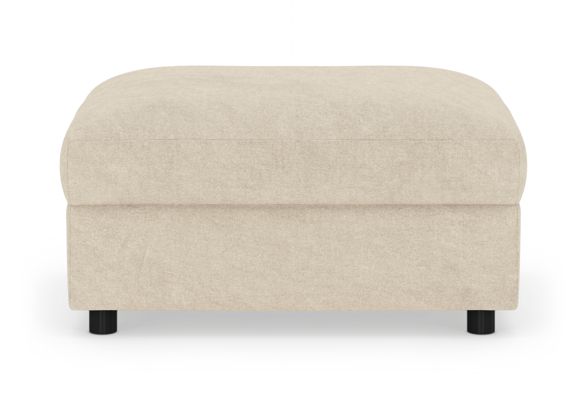 Beige puf/ottoman i stof med afrundede hjørner og sorte ben, frilagt på hvid baggrund.