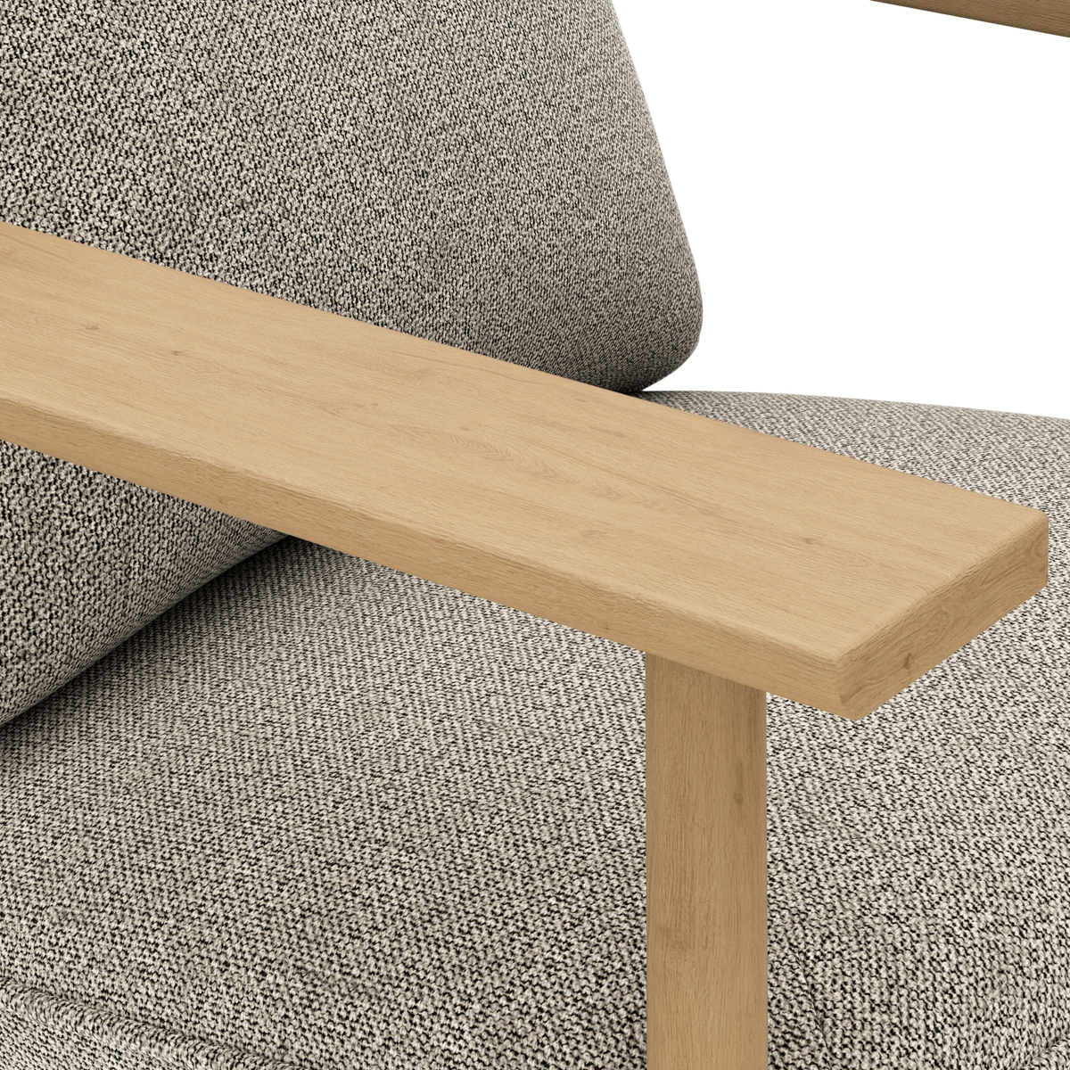 Nærbillede af et lyst egetræs armlæn på en grå, tekstureret sofa med pude.