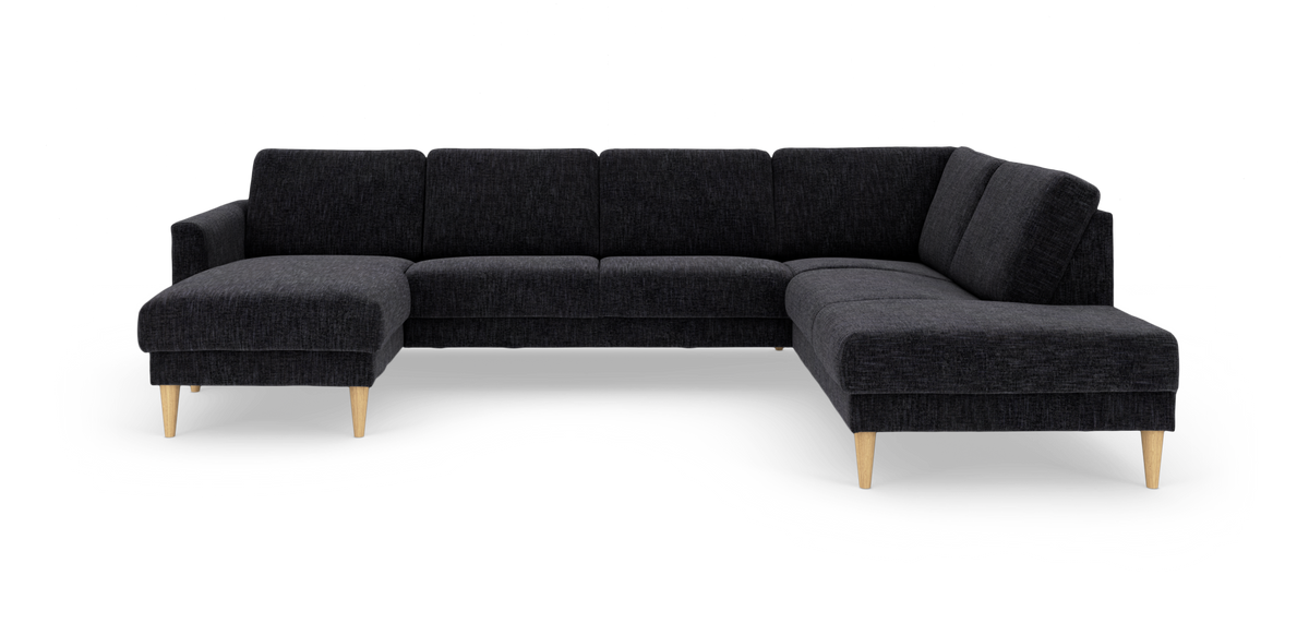 Mørkegrå U‑sofa i stof med venstre chaiselong og højre divan, koniske ben i lys træ.