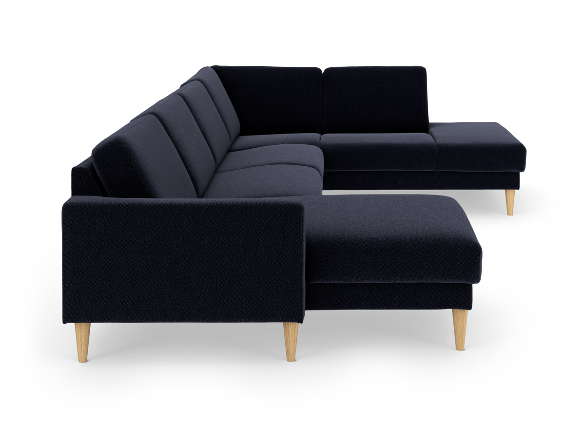 Mørkeblå hjørnesofa i stof med chaiselong og lyse, koniske træben.