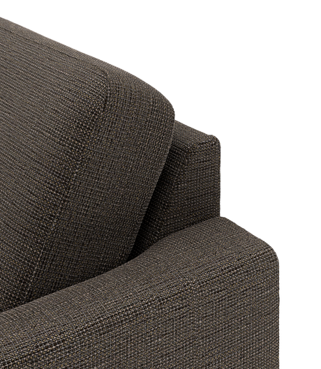 Nærbillede af et mørk gråbrunt sofa-hjørne med tekstureret stof og skråt rygpude.