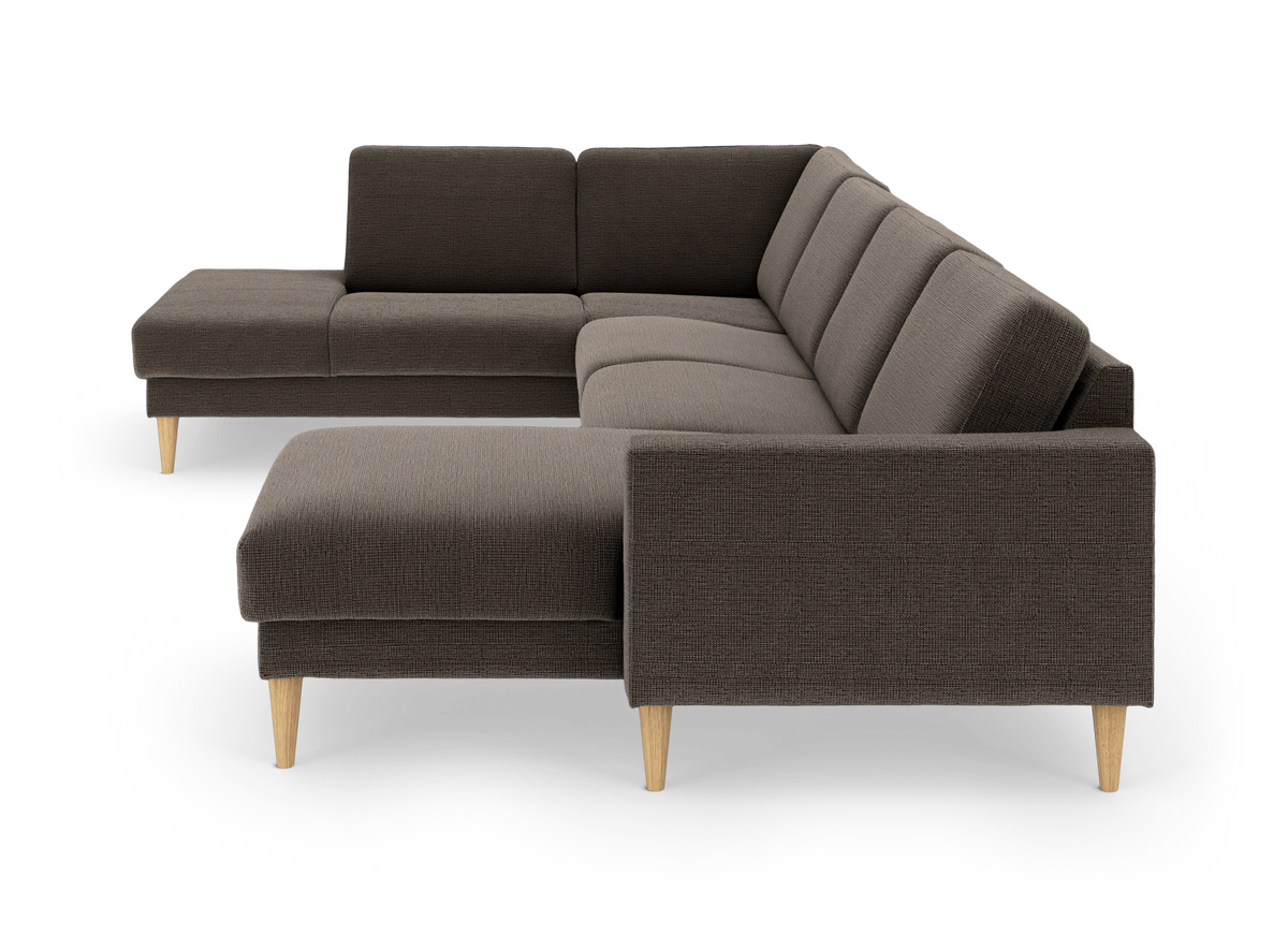 Modulær L‑sofa i mørkebrunt stof med chaiselong og lyse træben, fotograferet i studie fra front i vinkel.