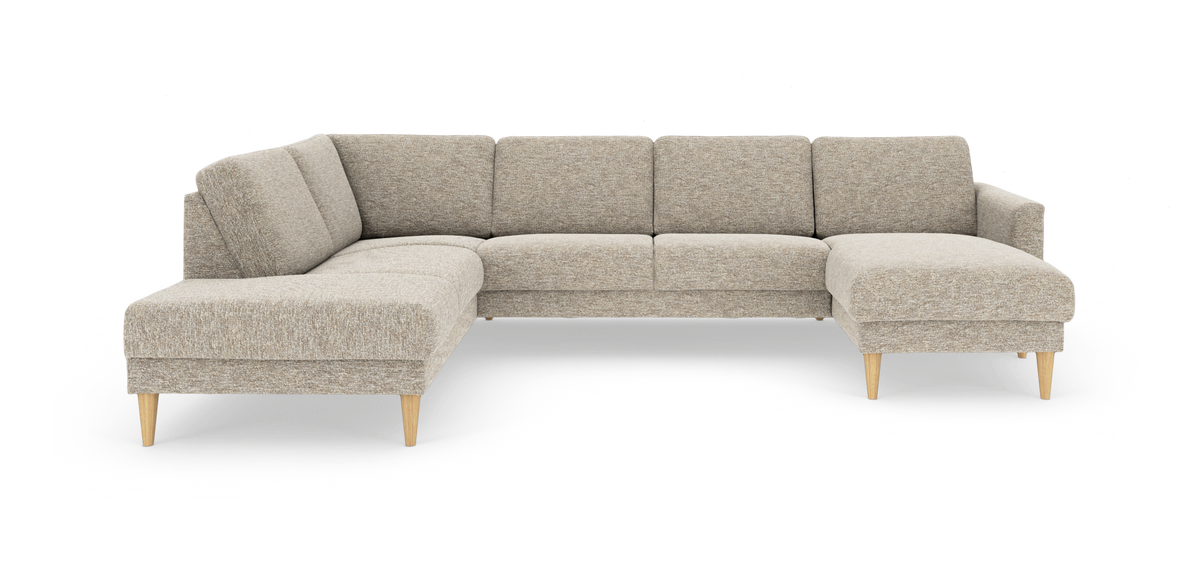 Beige modulsofa i L‑form med chaiselong til højre og koniske ben i lyst træ, frilagt på hvid baggrund.