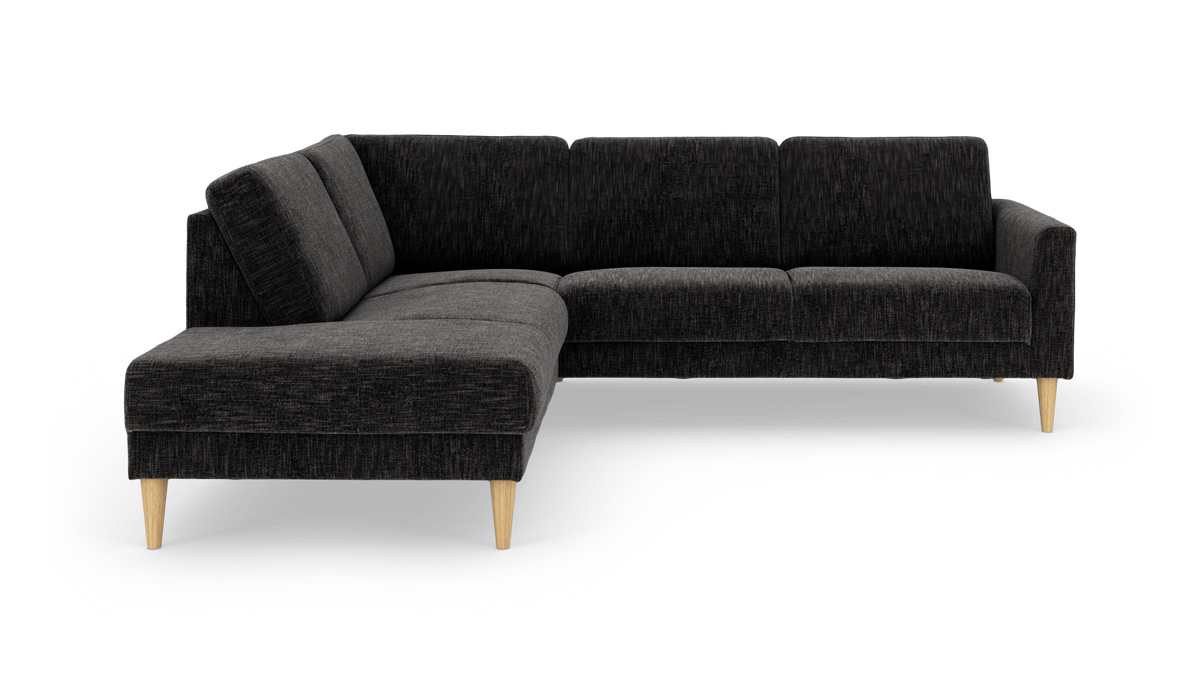 Mørkegrå L‑formet hjørnesofa med chaiselong og koniske ben i lyst træ, frilagt på hvid baggrund.