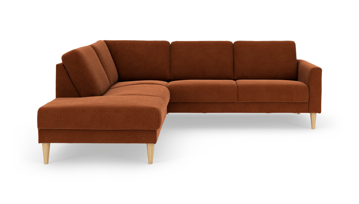 Rustfarvet L-formet hjørnesofa med chaiselong til venstre og koniske lyse træben, fritstående på hvid baggrund.