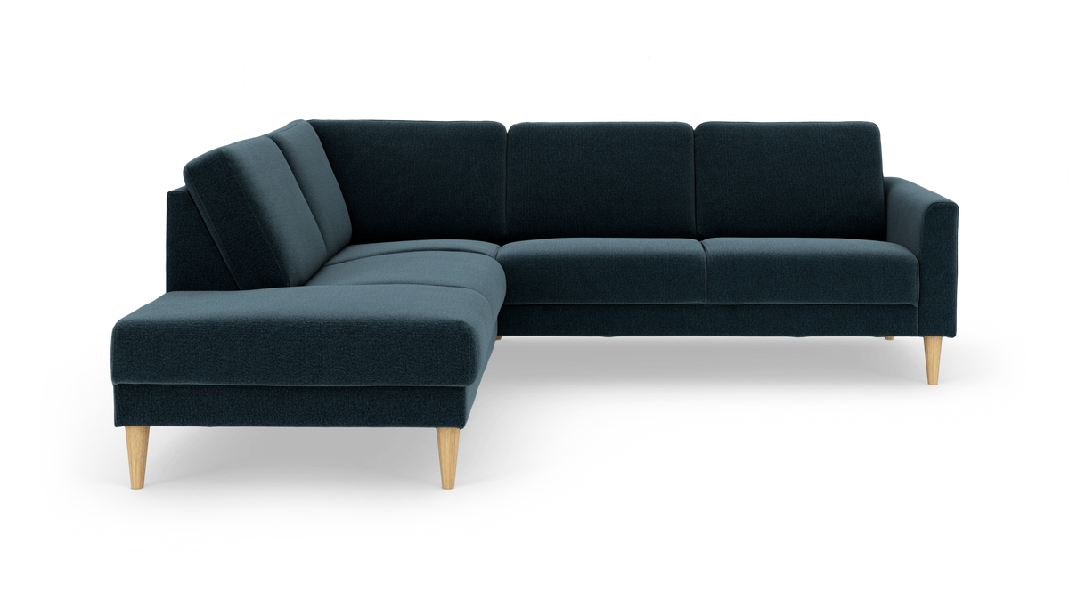 Mørkeblå hjørnesofa med chaiselong til venstre og koniske træben, frilagt på hvid baggrund.