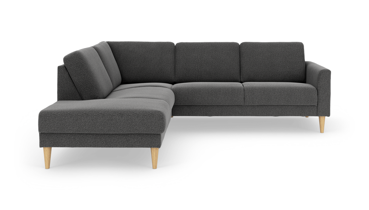 Mørkegrå hjørnesofa med venstrevendt chaiselong og koniske ben i lyst træ, frilagt på hvid baggrund.